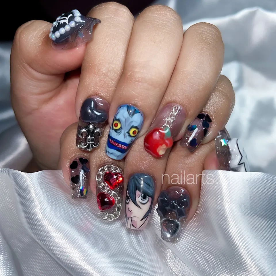 Uñas grises y negras con personajes de anime, una manzana roja y cristales