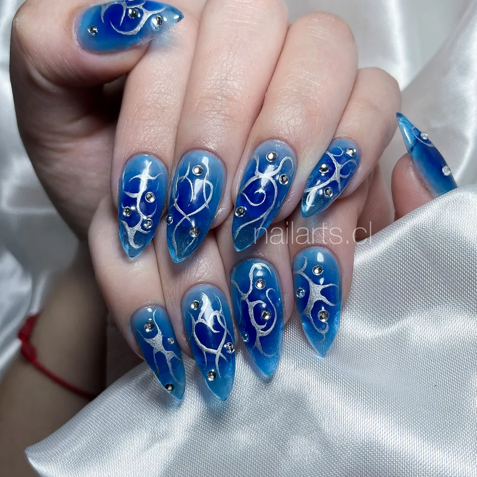 Uñas stiletto azules con dibujos de línea fina en blanco