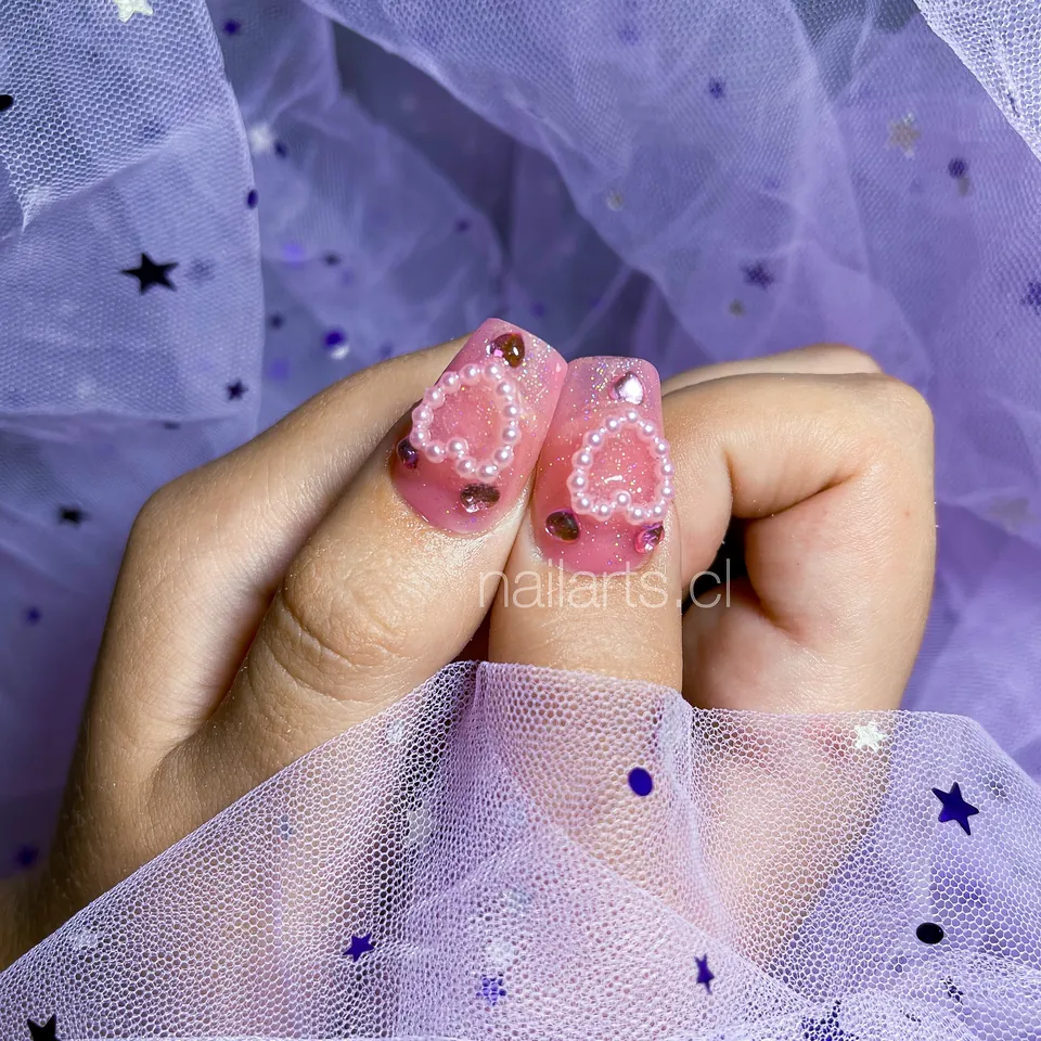 Uñas rosadas con corazones de perlas en relieve